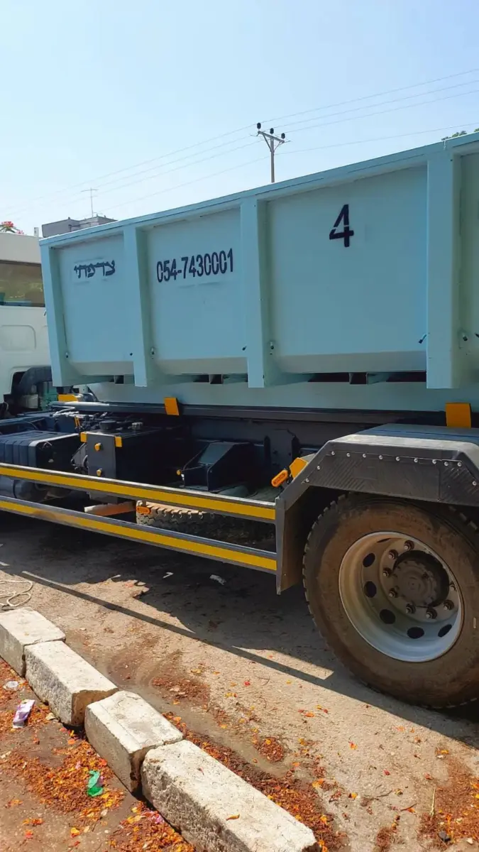 מכולה על משאית הרמה בדרך לאתר עבודה